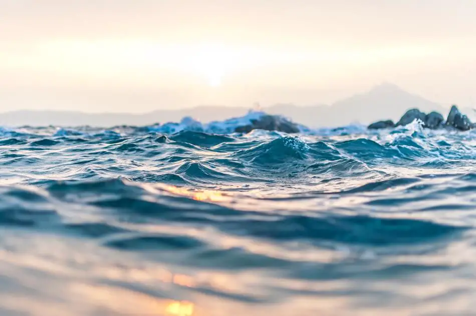 The surface of the water with a sunset behind it