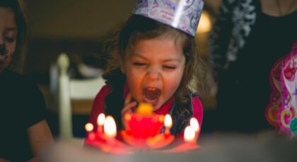 Girl blowing out candles after being told birthday puns and jokes