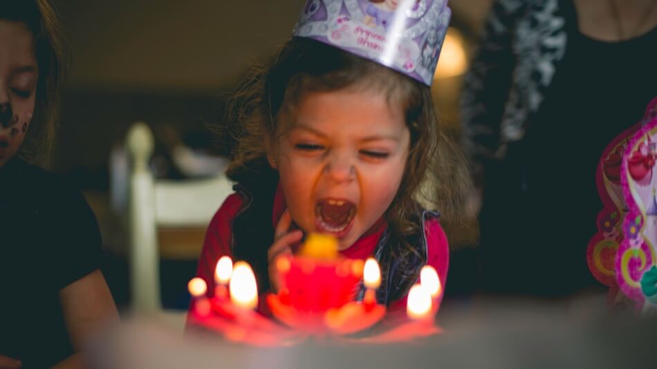 Girl blowing out candles after being told birthday puns and jokes