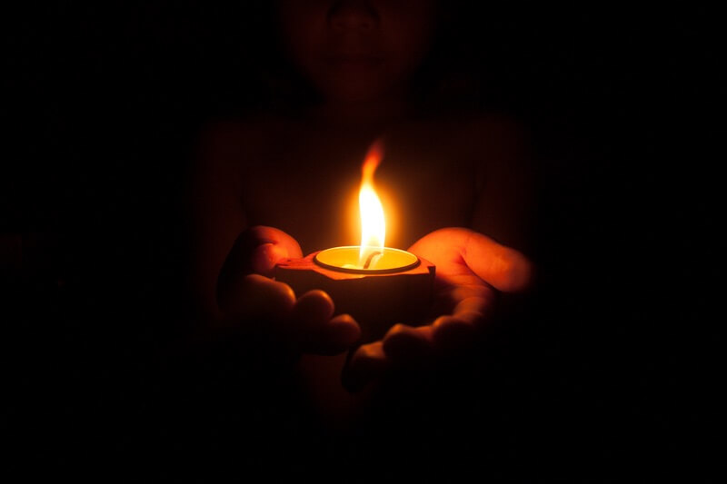 A woman holding a candle while telling puns and jokes about it